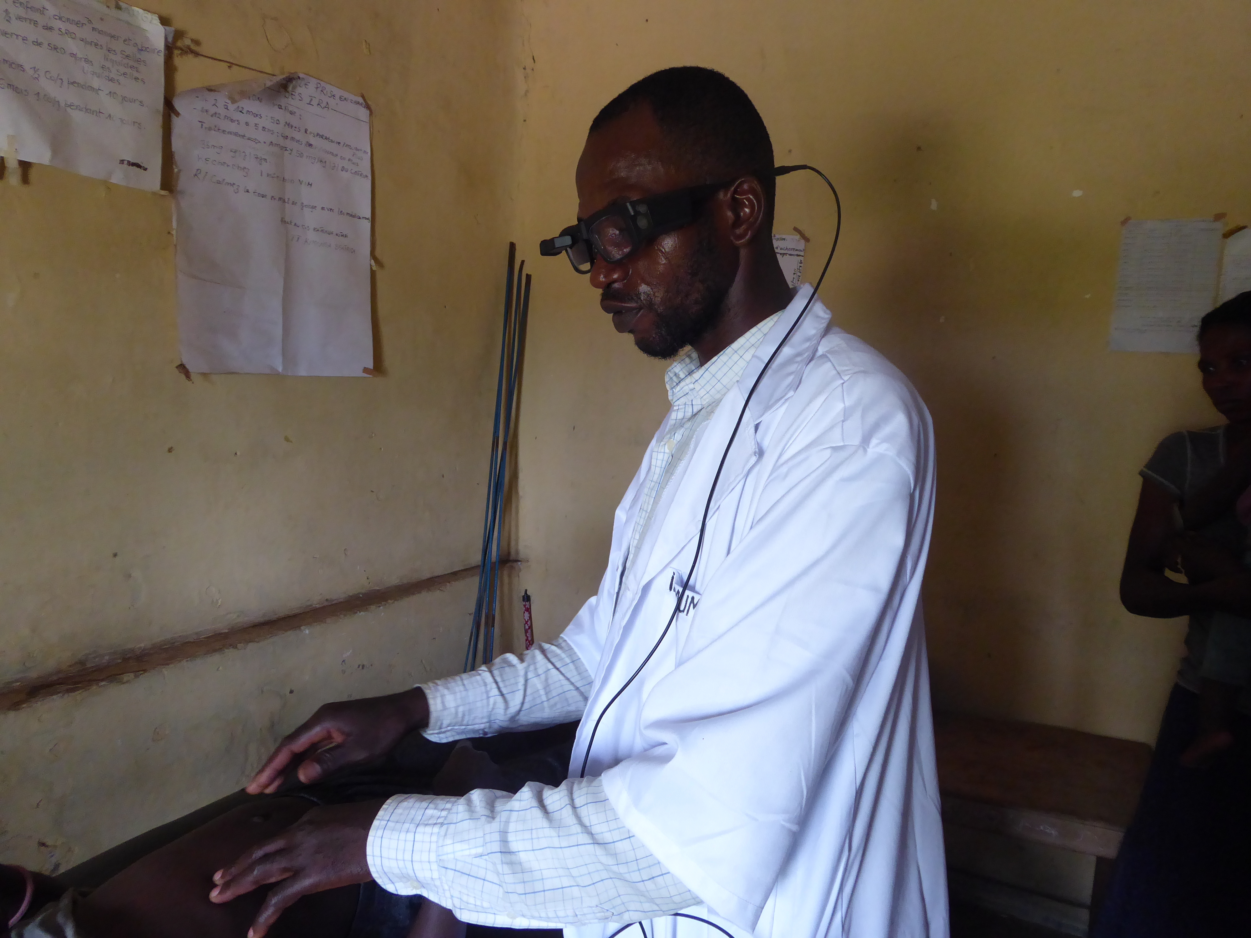 Nurse at Kigandu health center wearing smart glasses to examine a patient